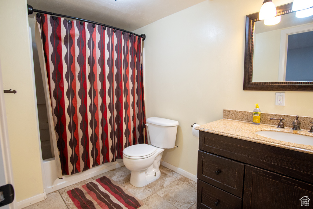 Full bath with baseboards, vanity, toilet, and shower / bath combo