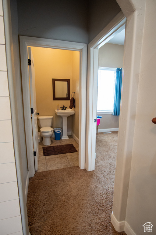 Half bath with toilet, baseboards, and a sink