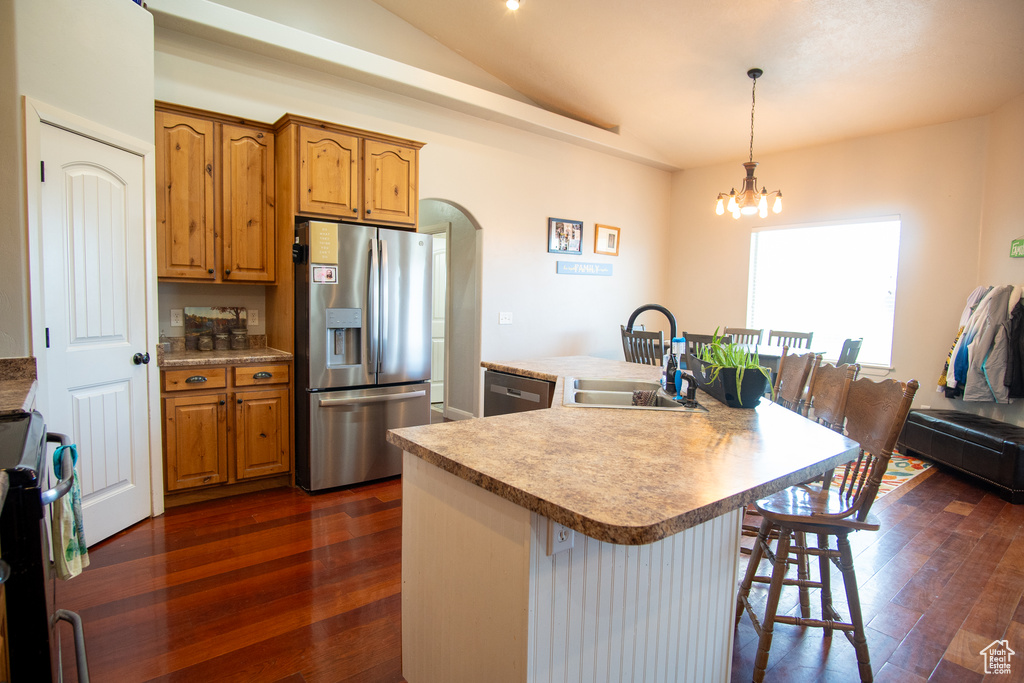 Kitchen with stainless steel appliances, a sink, dark wood-style flooring, a breakfast bar, and lofted ceiling