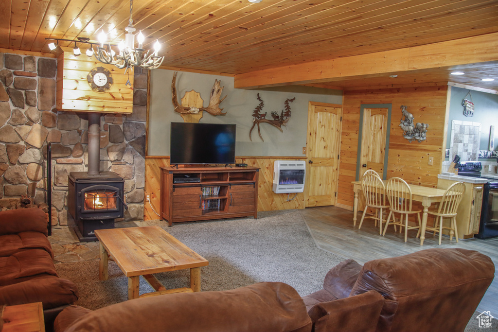 Living room featuring wood walls, heating unit, wood ceiling, a wood stove, and a chandelier