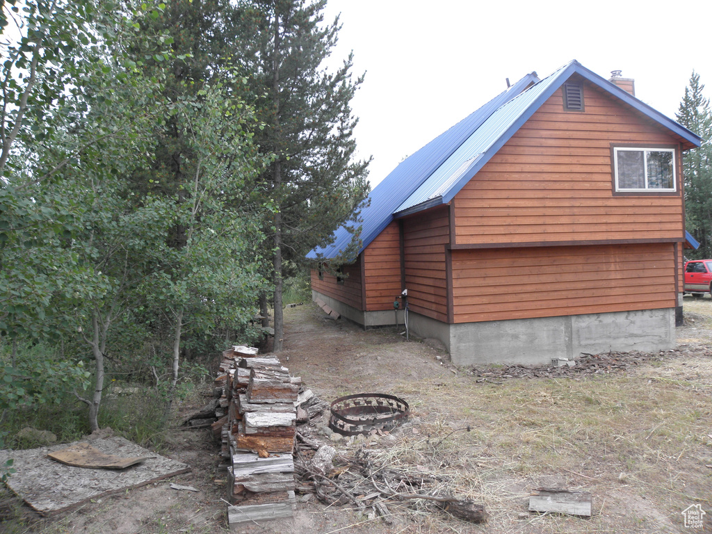 View of side of home with an outdoor fire pit, metal roof, and a chimney