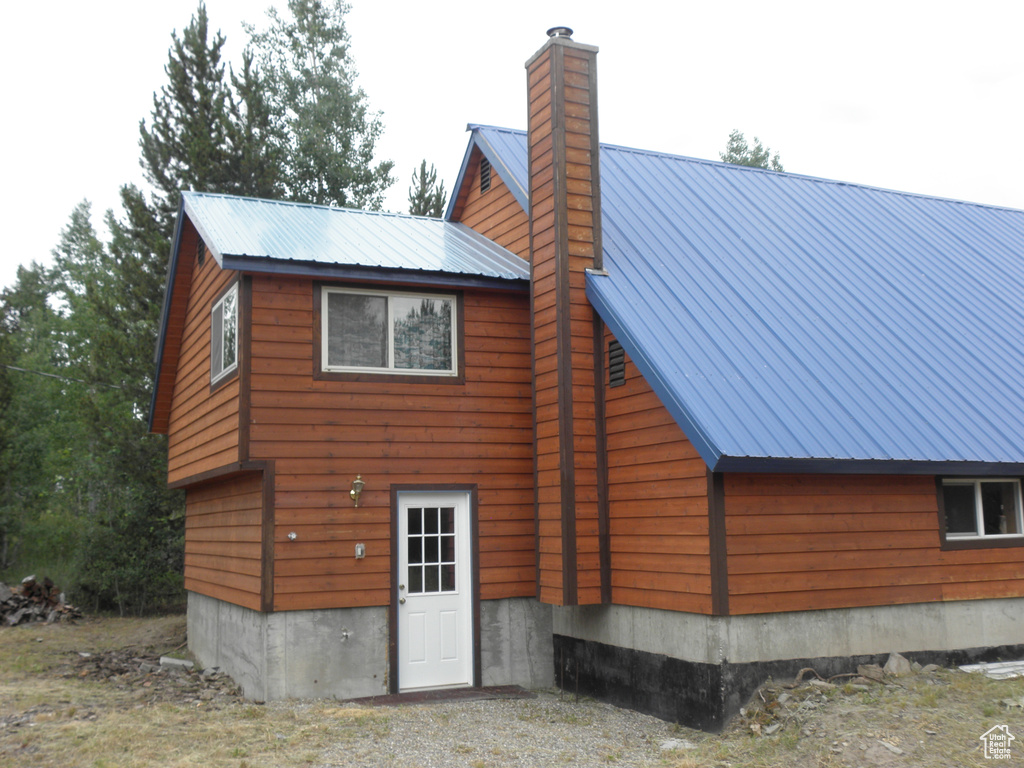 Rear view of property with a chimney and metal roof