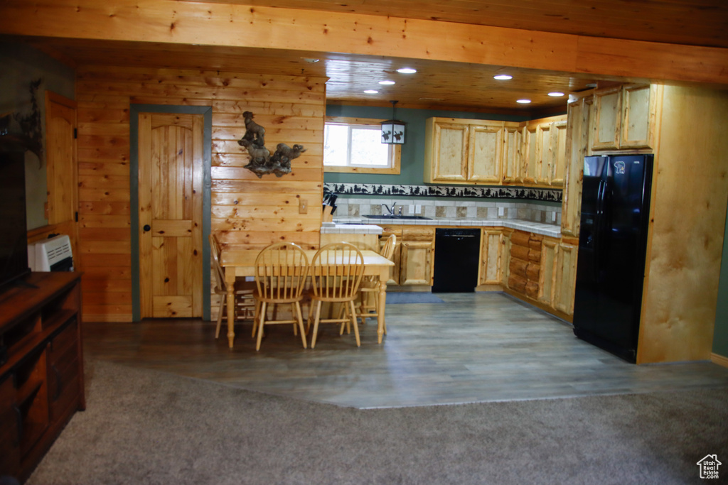 Kitchen featuring black appliances, a sink, light countertops, recessed lighting, and wooden walls