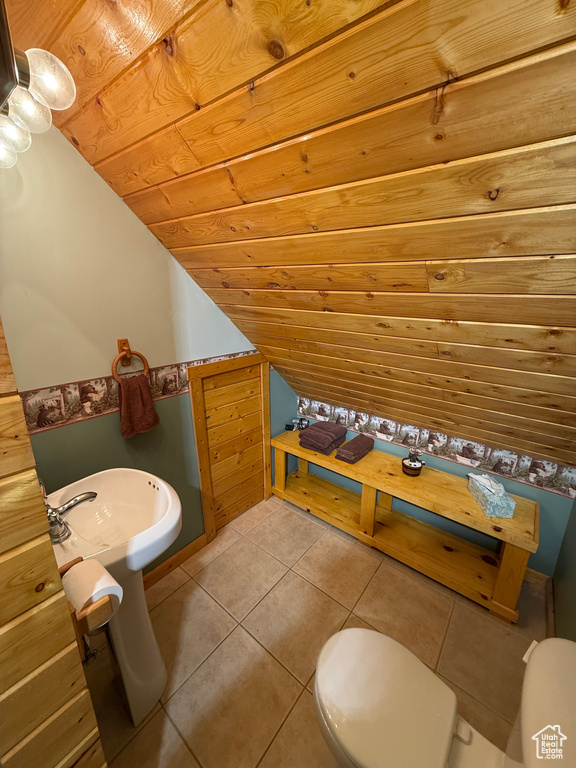 Half bathroom featuring toilet, lofted ceiling, tile patterned floors, a sink, and wooden ceiling