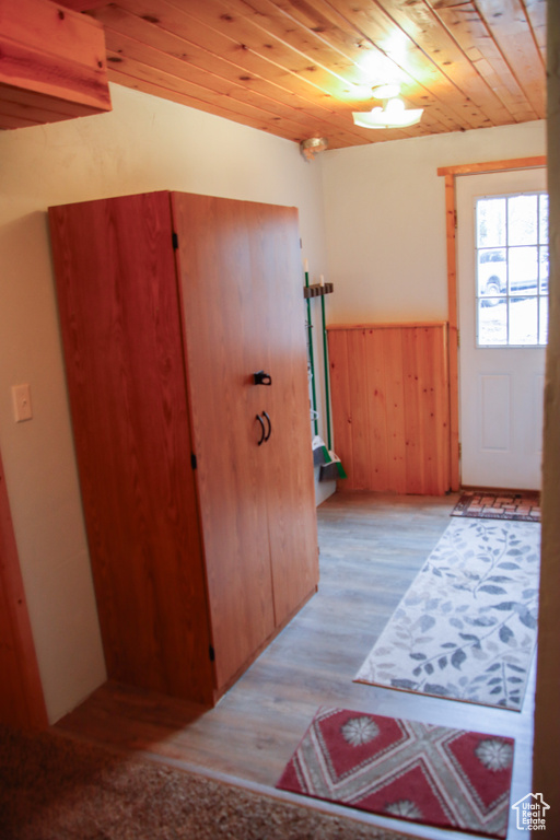Entrance foyer with wooden ceiling, wood finished floors, a wainscoted wall, and wood walls