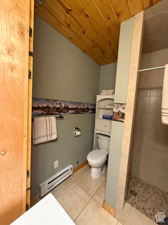 Bathroom with baseboard heating, toilet, tiled shower, tile patterned flooring, and wooden ceiling