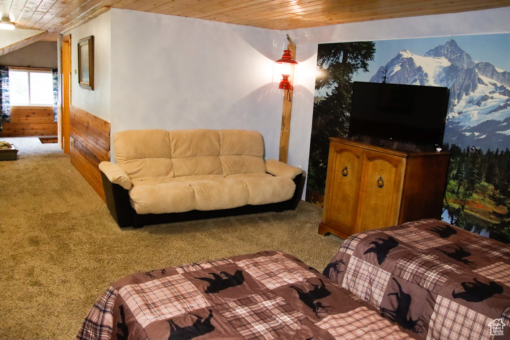 Carpeted bedroom featuring wooden ceiling and wood walls