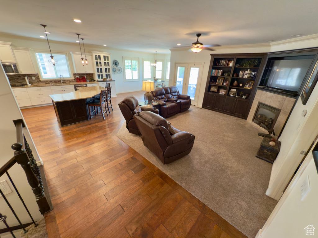 Living area featuring a tile fireplace, ceiling fan, wood finished floors, and recessed lighting