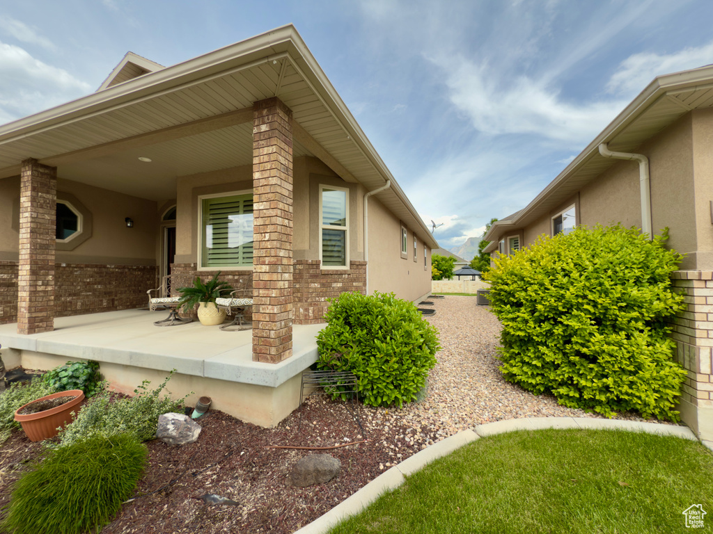 View of side of property with stucco siding, covered porch, and brick siding