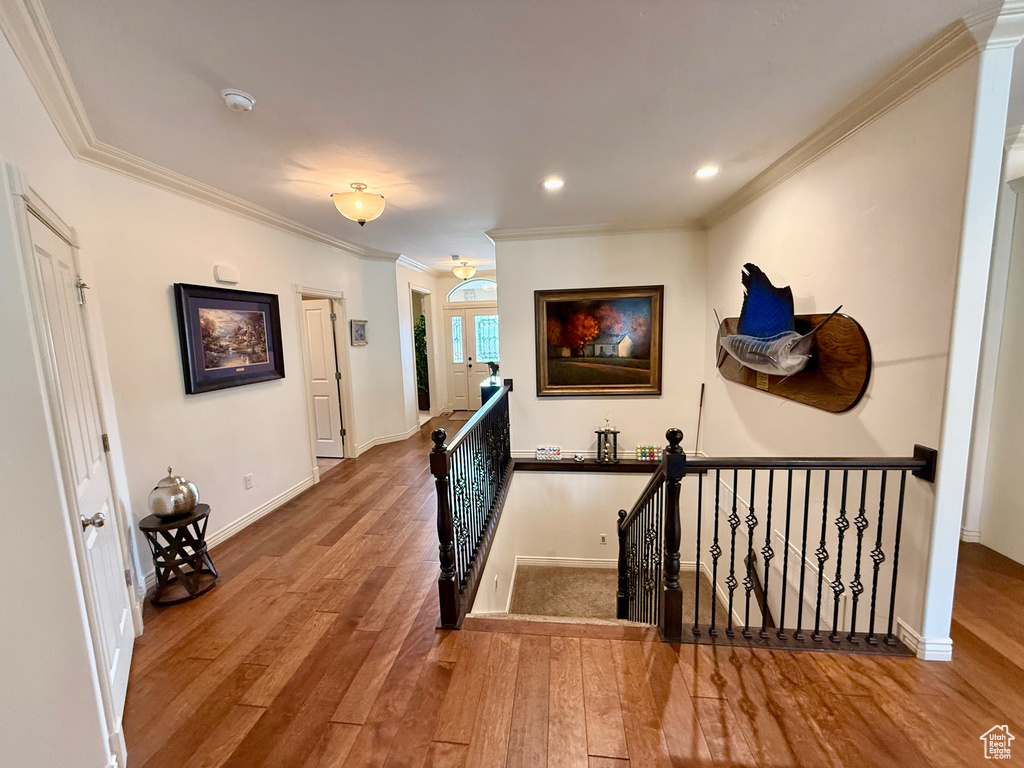 Corridor featuring an upstairs landing, wood finished floors, ornamental molding, recessed lighting, and baseboards