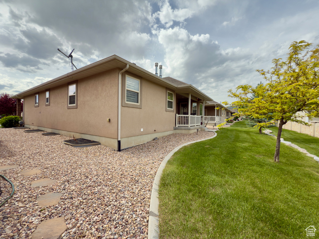 Back of house featuring covered porch, a lawn, and stucco siding
