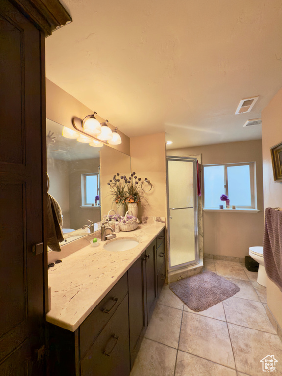 Bathroom with vanity, a shower stall, toilet, tile patterned floors, and baseboards