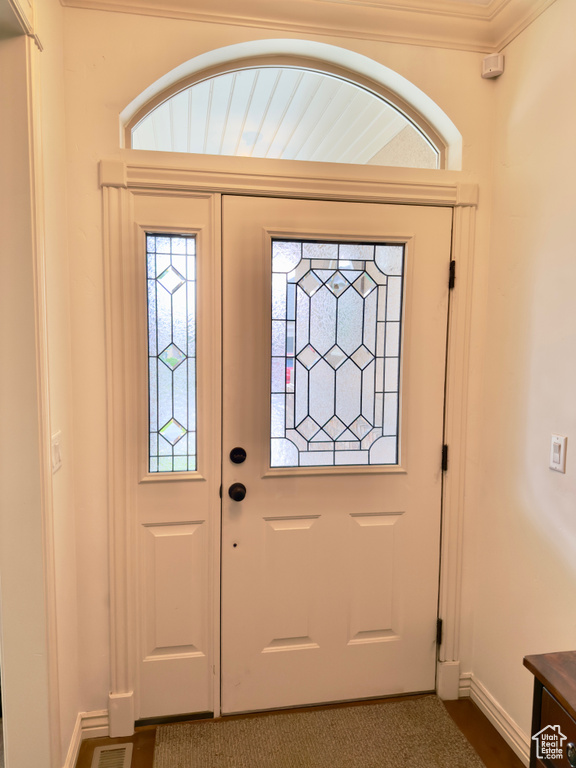 Entrance foyer featuring baseboards, ornamental molding, and dark colored carpet