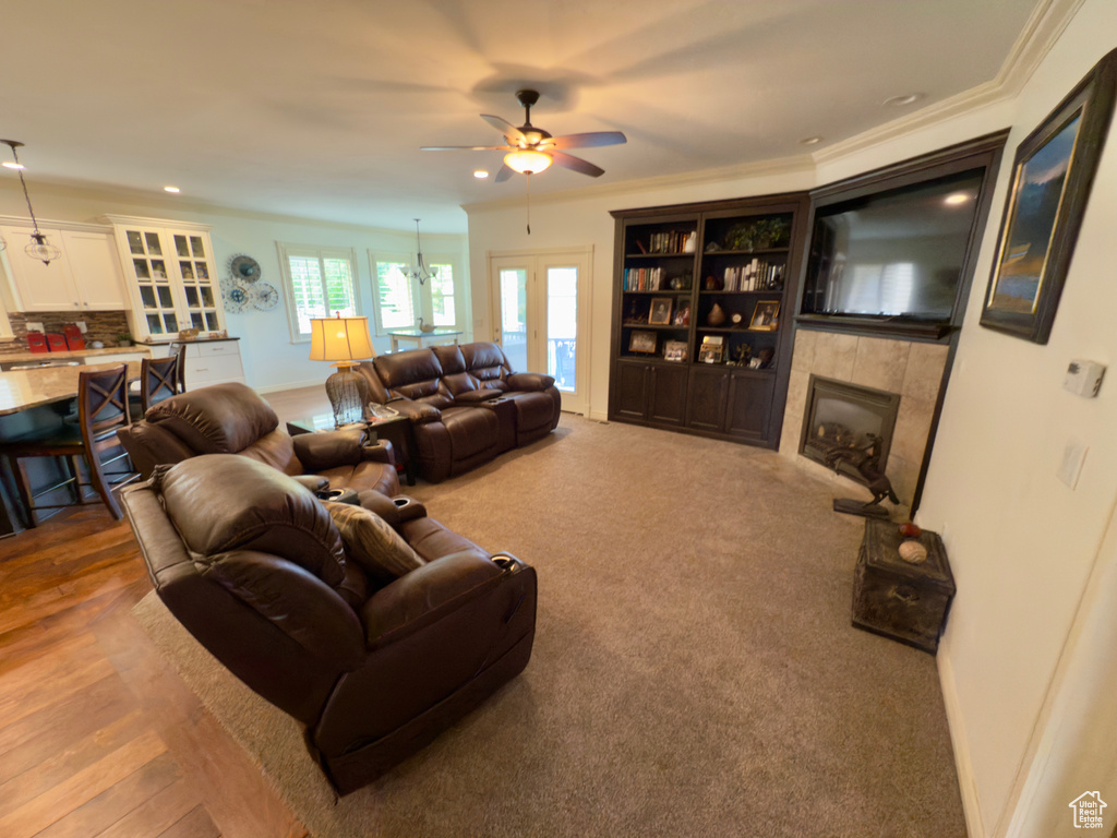 Living area with ceiling fan, a tile fireplace, recessed lighting, ornamental molding, and baseboards
