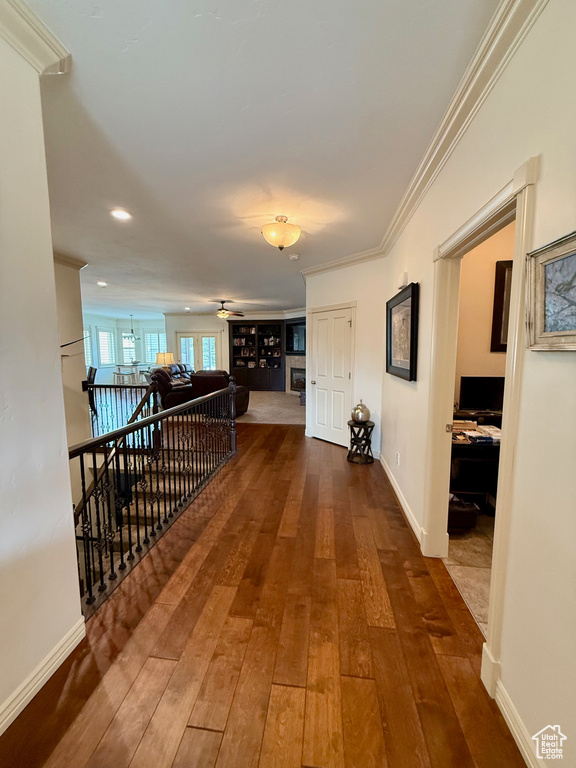 Hall with dark wood-style flooring, baseboards, and crown molding