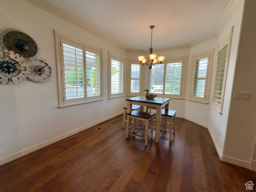 Dining area with a chandelier, dark wood-style floors, baseboards, and crown molding