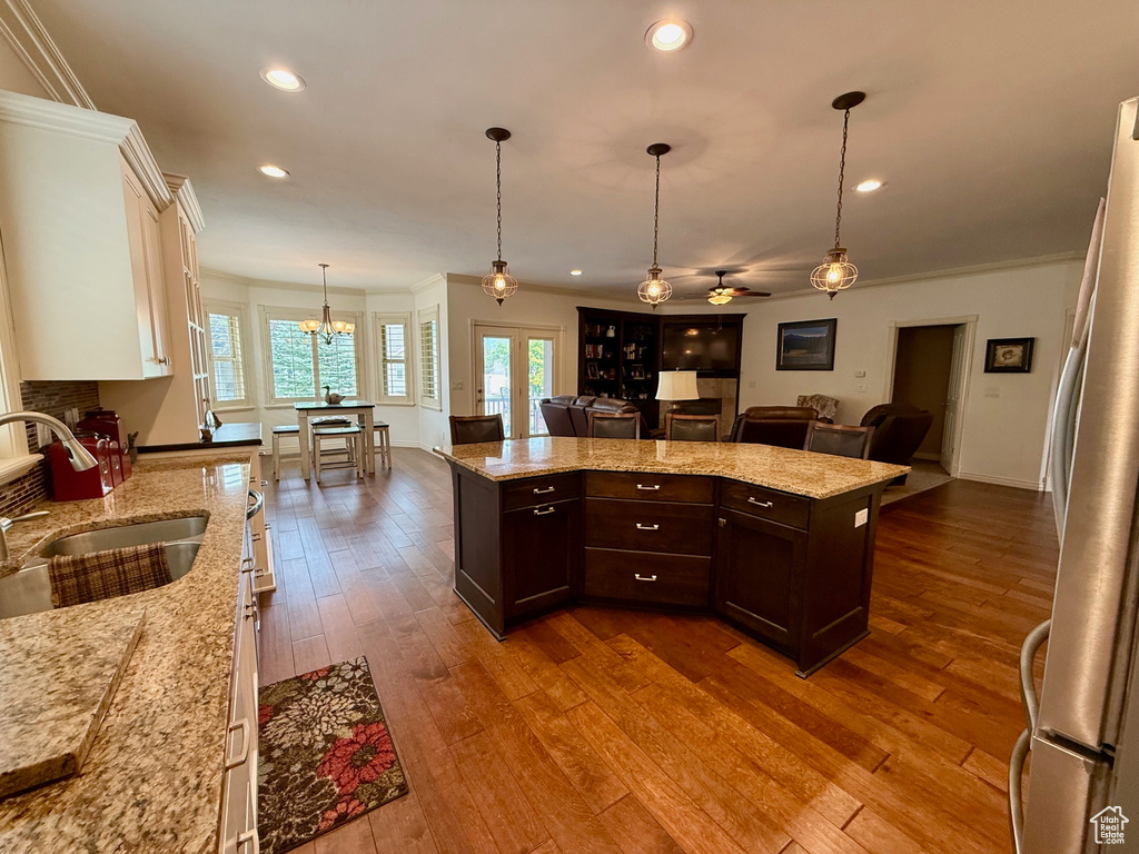 Kitchen with a sink, freestanding refrigerator, open floor plan, dark brown cabinetry, and white cabinets