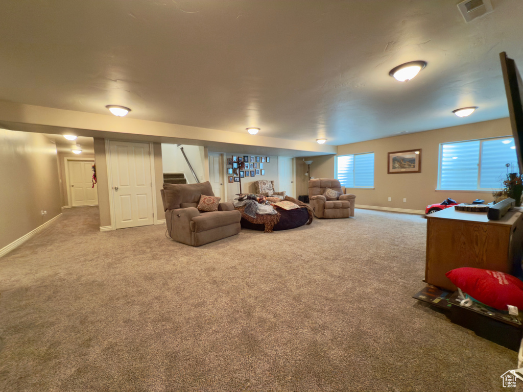 Living area with carpet flooring, baseboards, and stairs