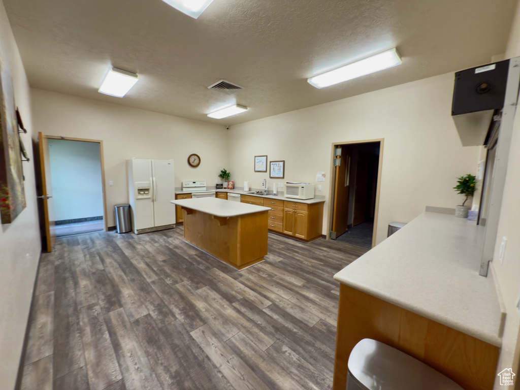 Kitchen with white appliances, light countertops, dark wood finished floors, a sink, and a textured ceiling
