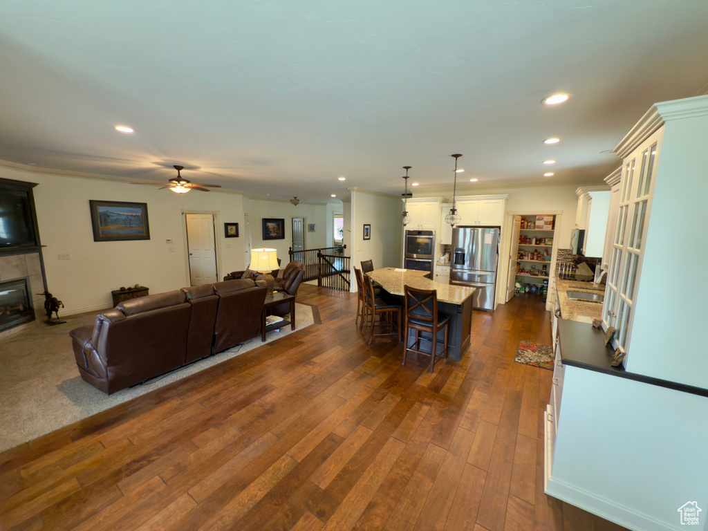 Living room featuring a fireplace, dark wood-style flooring, a ceiling fan, and recessed lighting