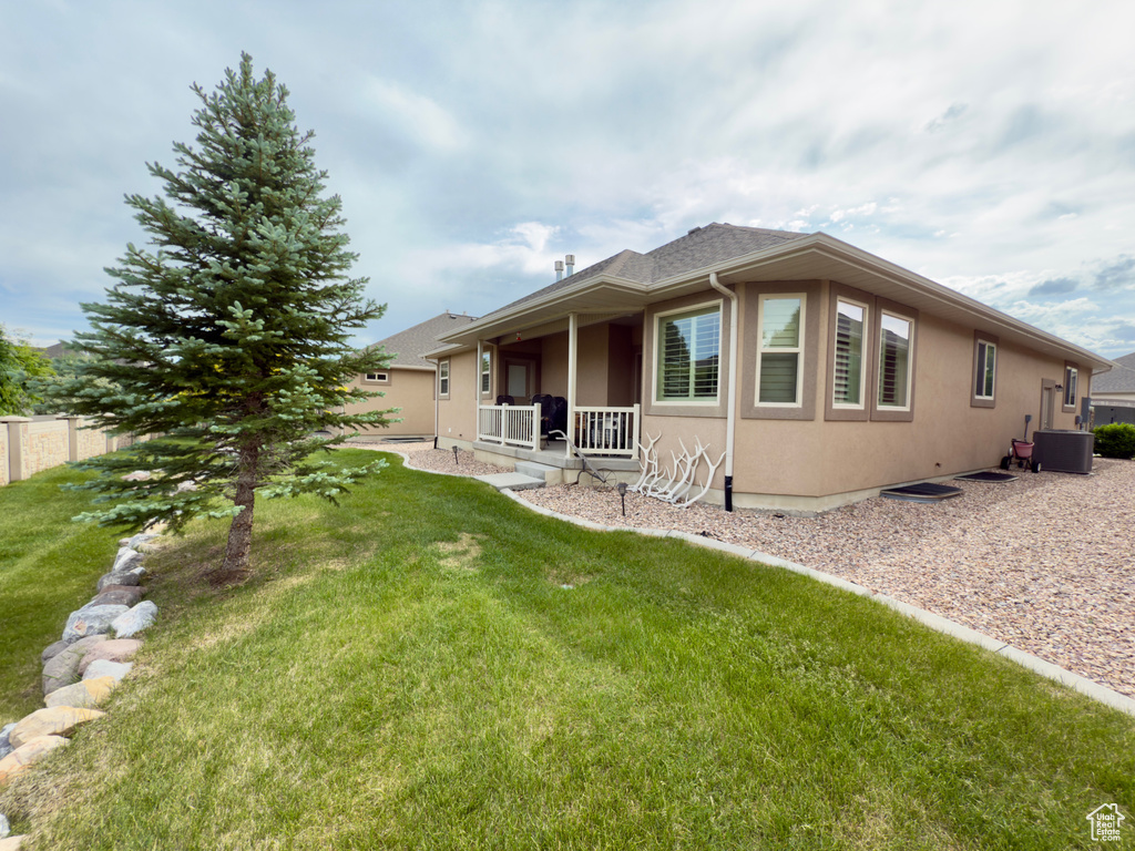 Back of property featuring stucco siding, a yard, covered porch, and cooling unit