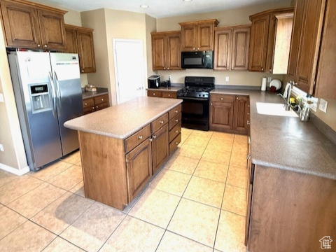 Kitchen featuring black appliances, a sink, a kitchen island, light tile patterned flooring, and recessed lighting