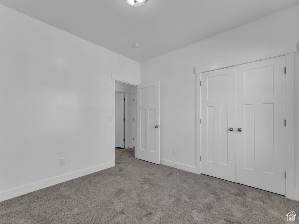 Unfurnished bedroom featuring carpet, baseboards, and a closet