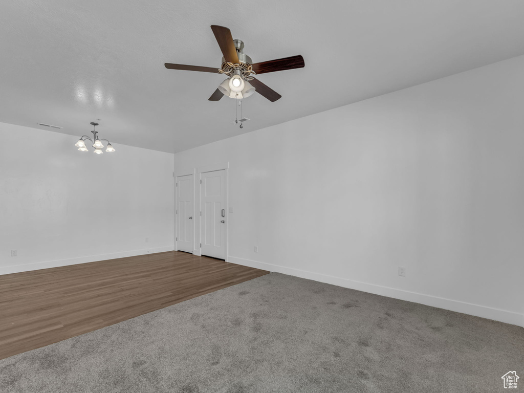 Unfurnished room featuring ceiling fan, a chandelier, baseboards, and carpet flooring