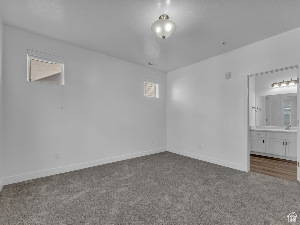 Unfurnished bedroom featuring carpet flooring, baseboards, connected bathroom, and a sink