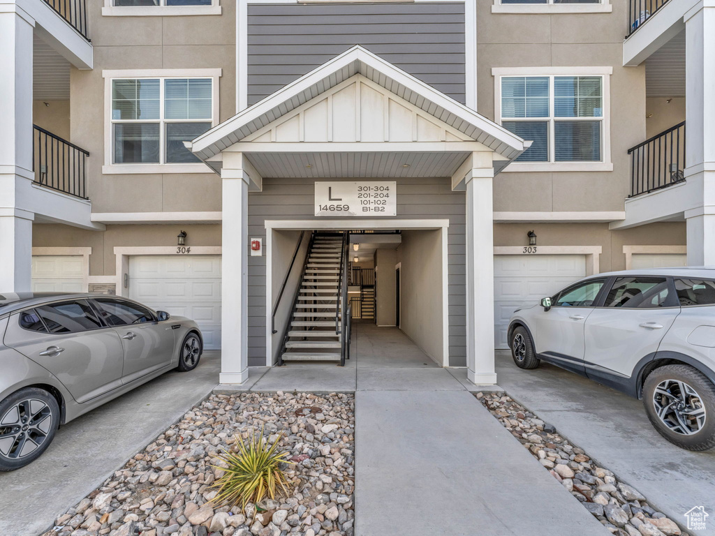 Property entrance featuring an attached garage, driveway, and stucco siding