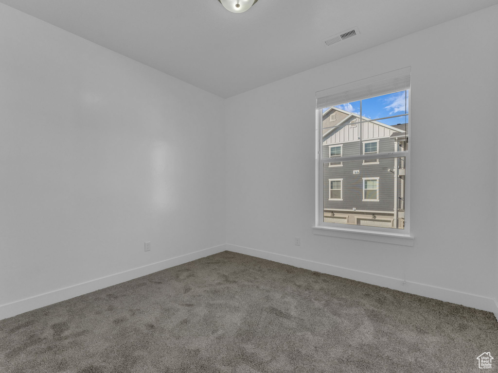 Spare room featuring carpet flooring and baseboards