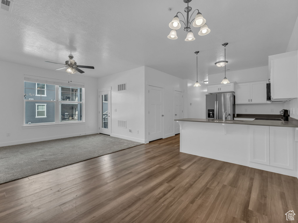 Kitchen with a ceiling fan, a peninsula, dark countertops, white cabinets, and open floor plan