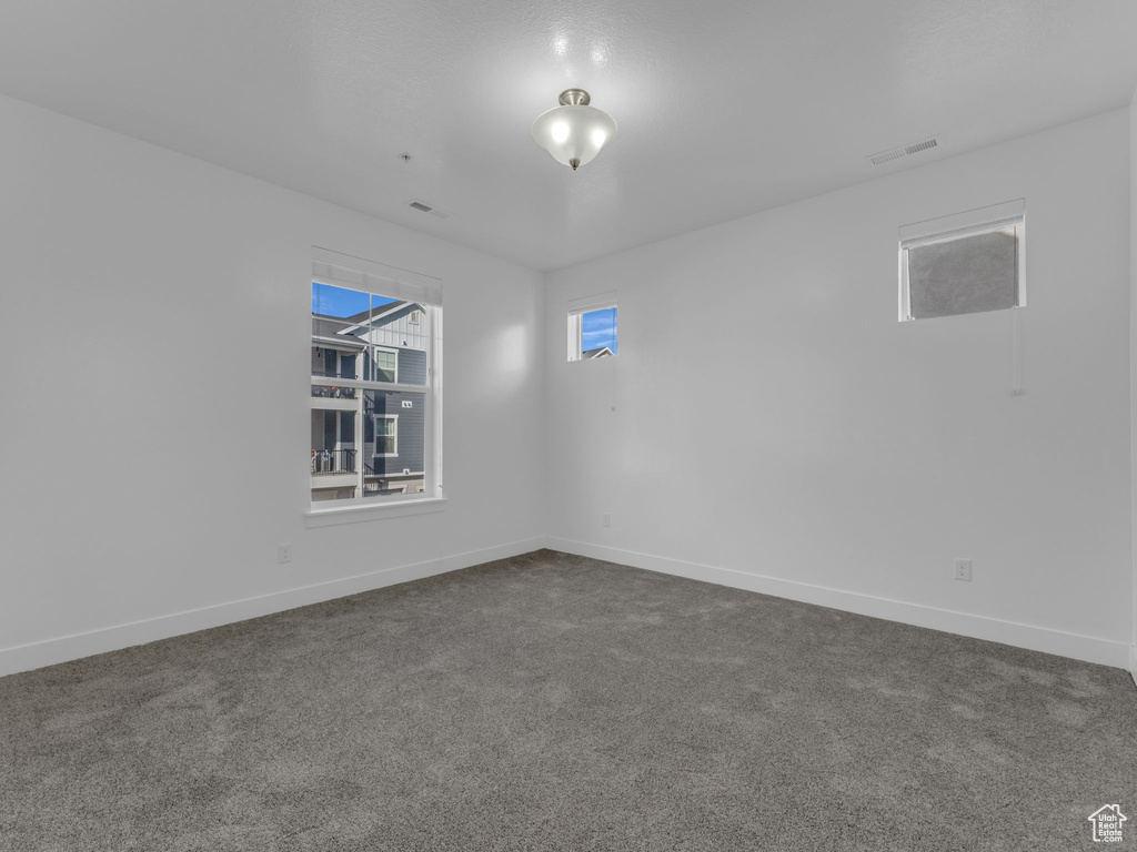 Unfurnished room featuring dark carpet and baseboards