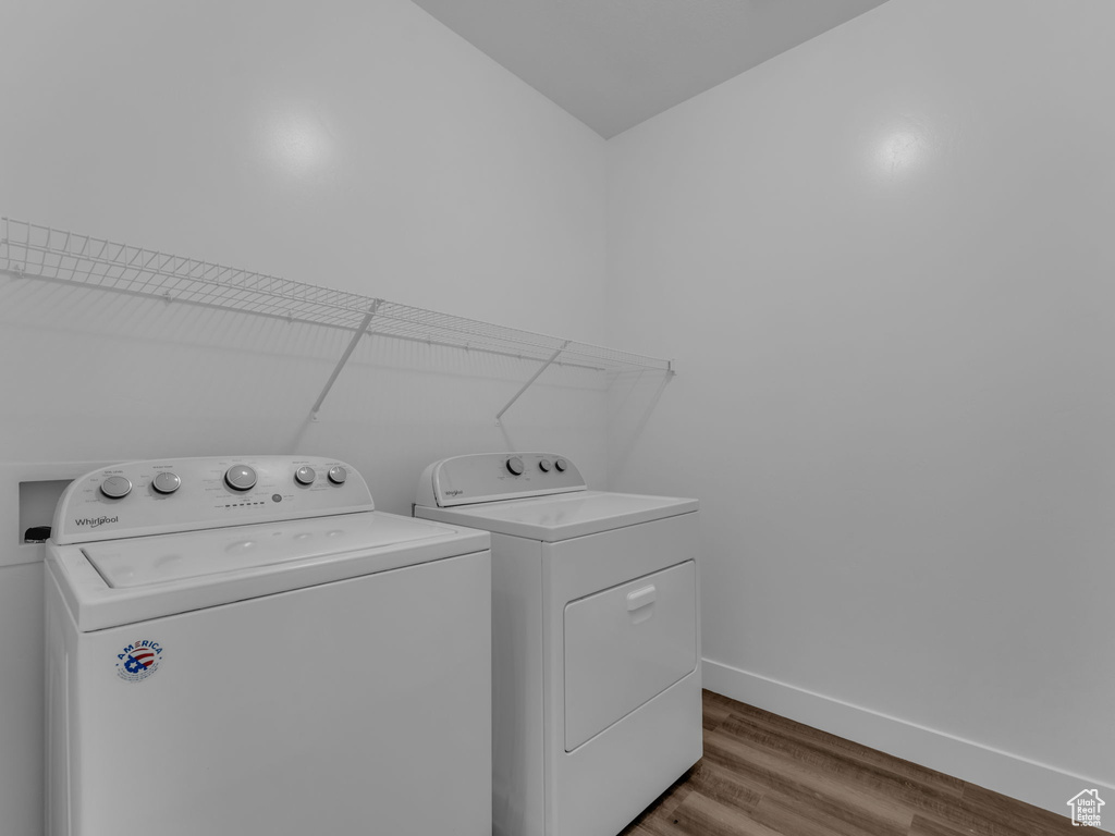 Laundry room with washer and dryer, wood finished floors, and baseboards