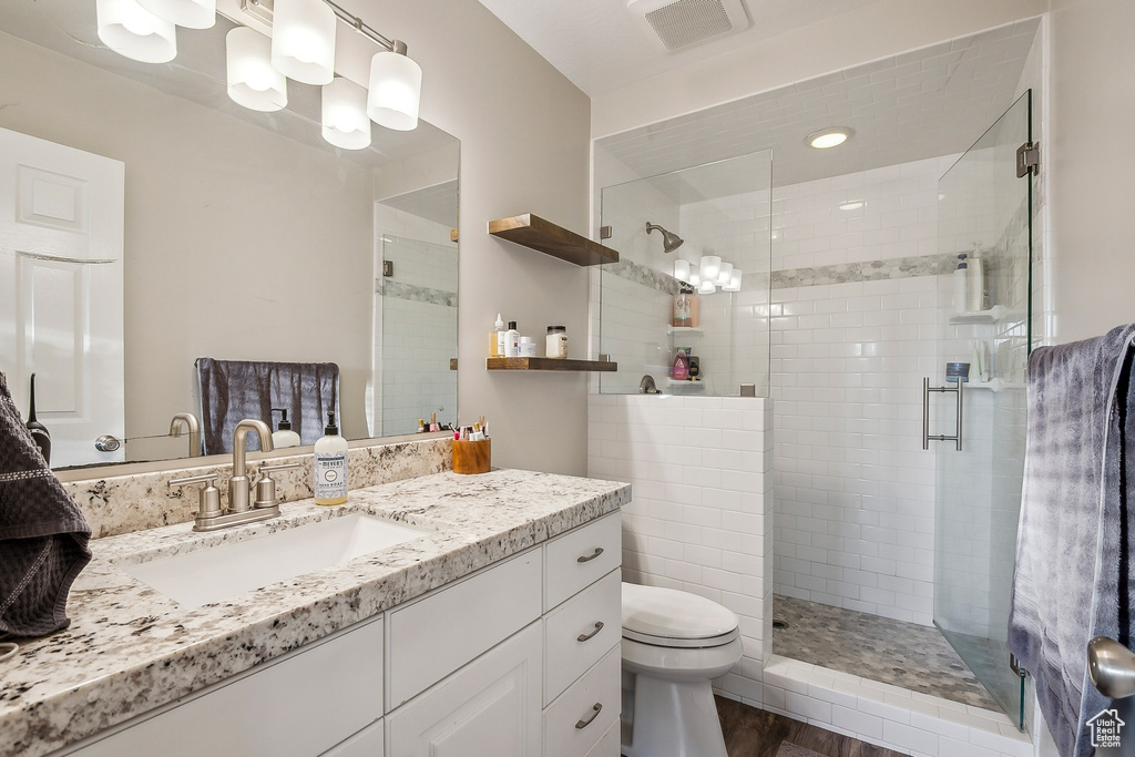 Full bath with toilet, vanity, a shower stall, and wood finished floors