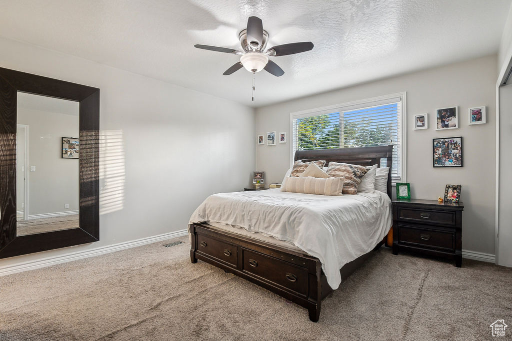 Bedroom with light carpet, baseboards, and a ceiling fan