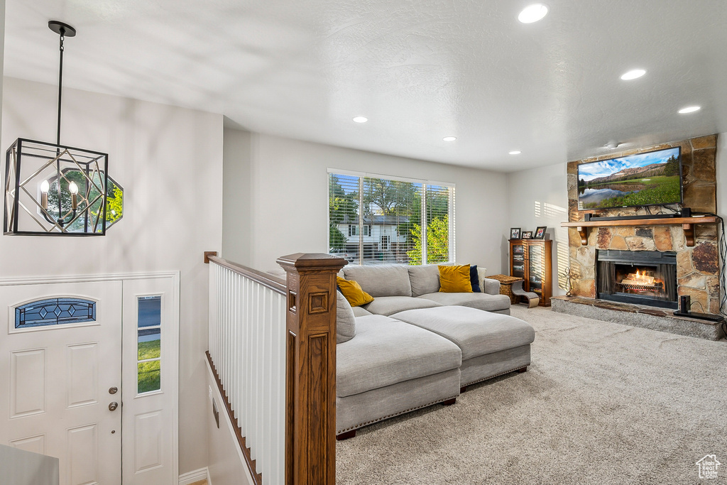 Living area with carpet floors, recessed lighting, a chandelier, and a stone fireplace