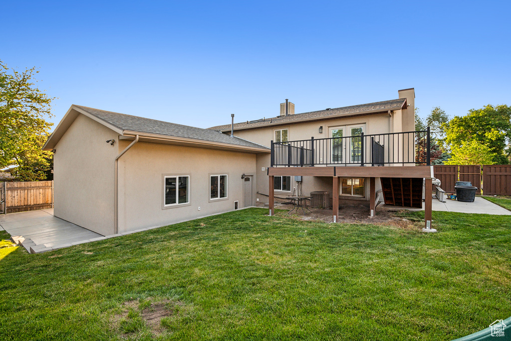Rear view of house with a patio, a deck, stucco siding, central AC, and a chimney