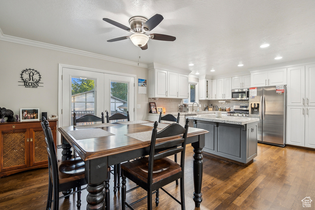 Dining room featuring healthy amount of natural light, a ceiling fan, crown molding, wood finished floors, and recessed lighting