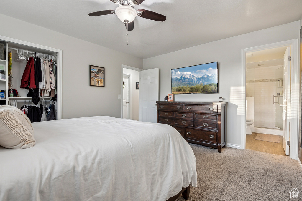 Bedroom with a closet, light colored carpet, ensuite bath, and a ceiling fan
