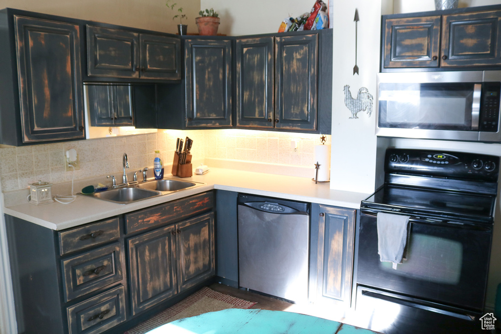 Kitchen with stainless steel appliances, a sink, light countertops, and decorative backsplash