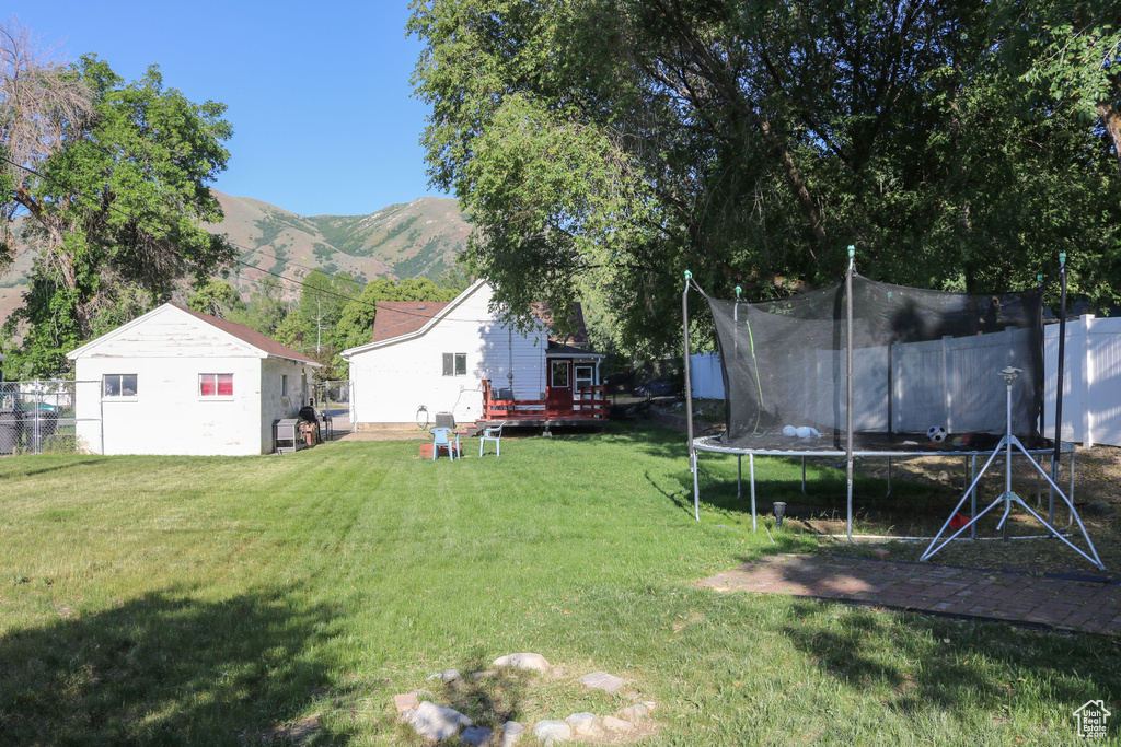 View of yard featuring a trampoline and a deck with mountain view