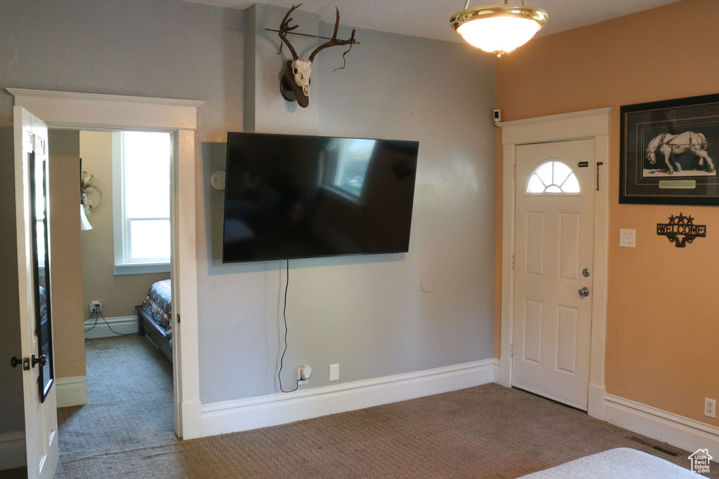 Carpeted entryway featuring a baseboard radiator and baseboards