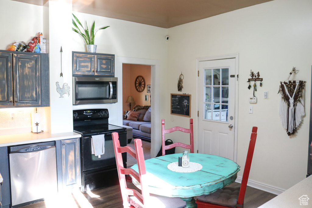 Kitchen featuring appliances with stainless steel finishes, dark wood-style flooring, light countertops, and baseboards