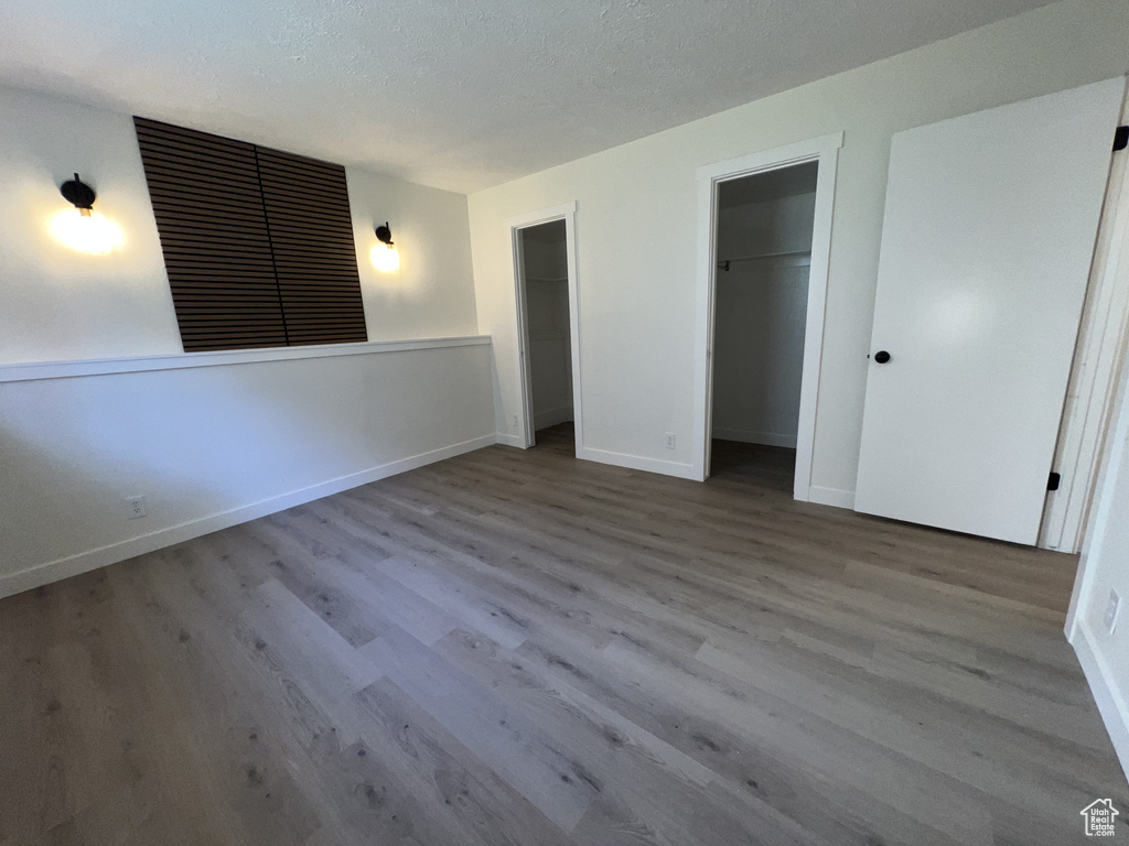 Unfurnished bedroom with wood finished floors, baseboards, and a textured ceiling
