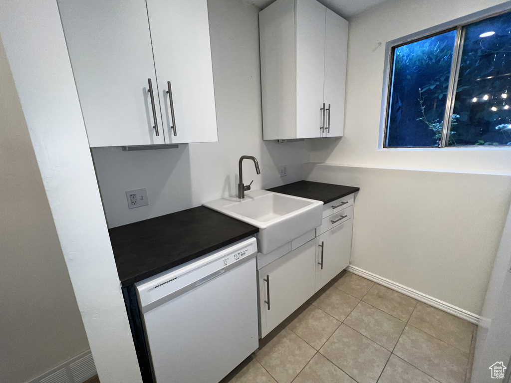 Kitchen with dishwasher, white cabinets, a sink, and light tile patterned floors