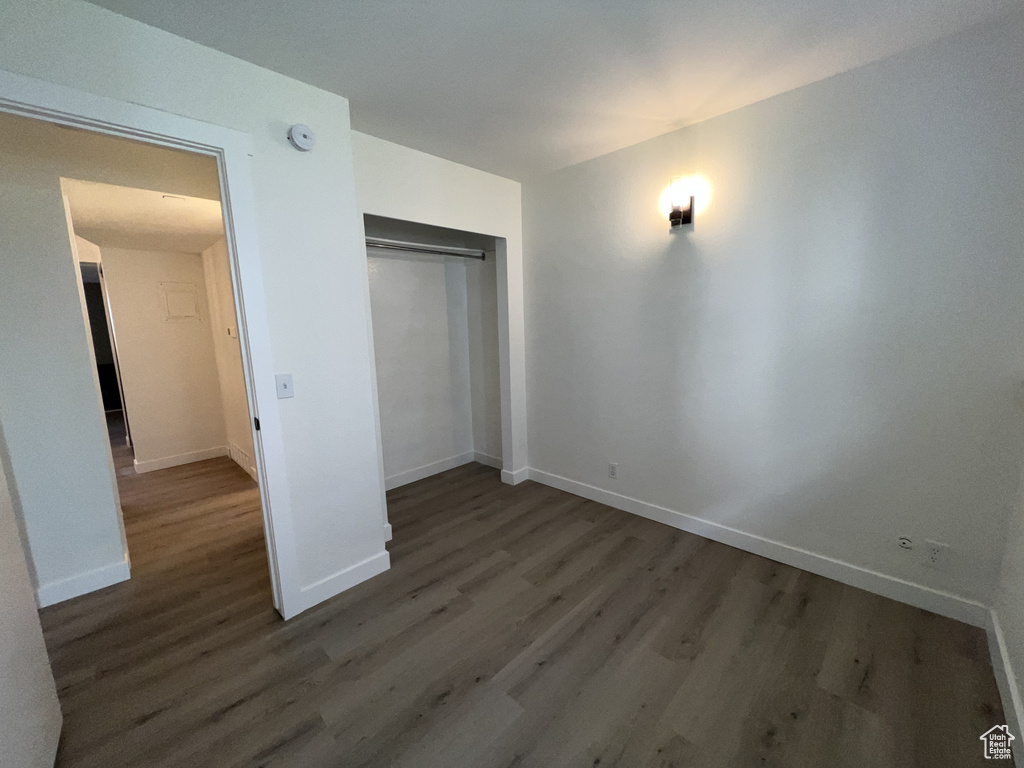 Unfurnished bedroom featuring wood finished floors, baseboards, and a closet