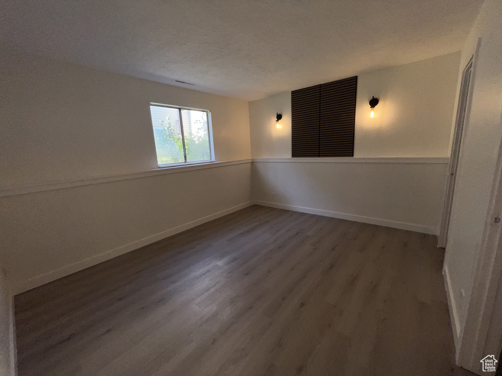 Spare room with wood finished floors, baseboards, and a textured ceiling