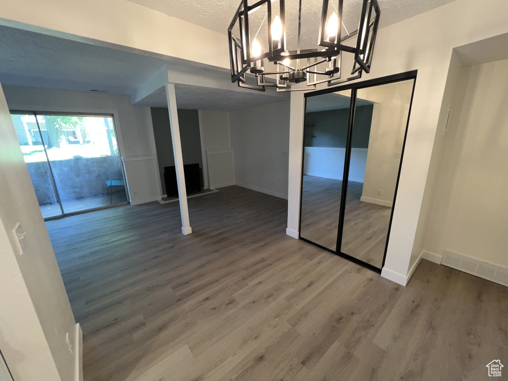 Unfurnished dining area featuring wood finished floors, baseboards, a chandelier, and a textured ceiling
