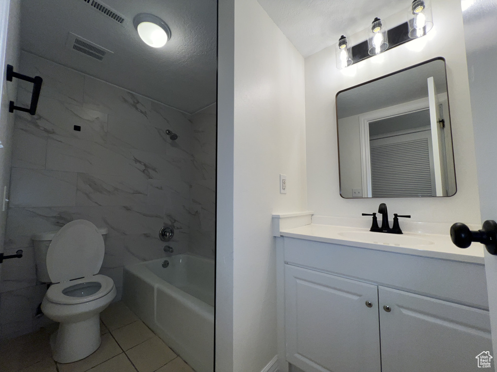 Full bathroom featuring toilet, vanity,  shower combination, and tile patterned flooring